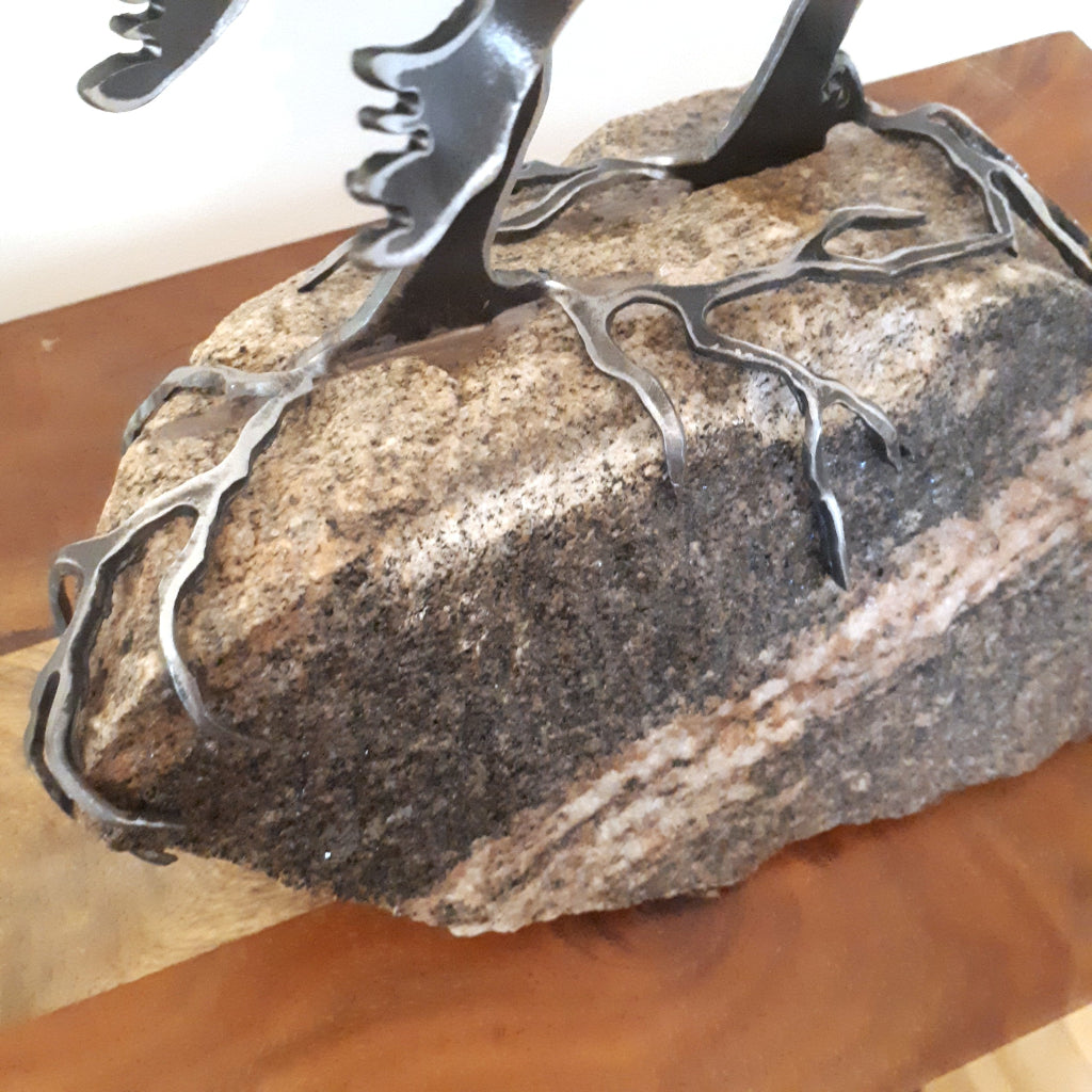 detail of metal roots of a tree sculpture on a piece of Canadian granite