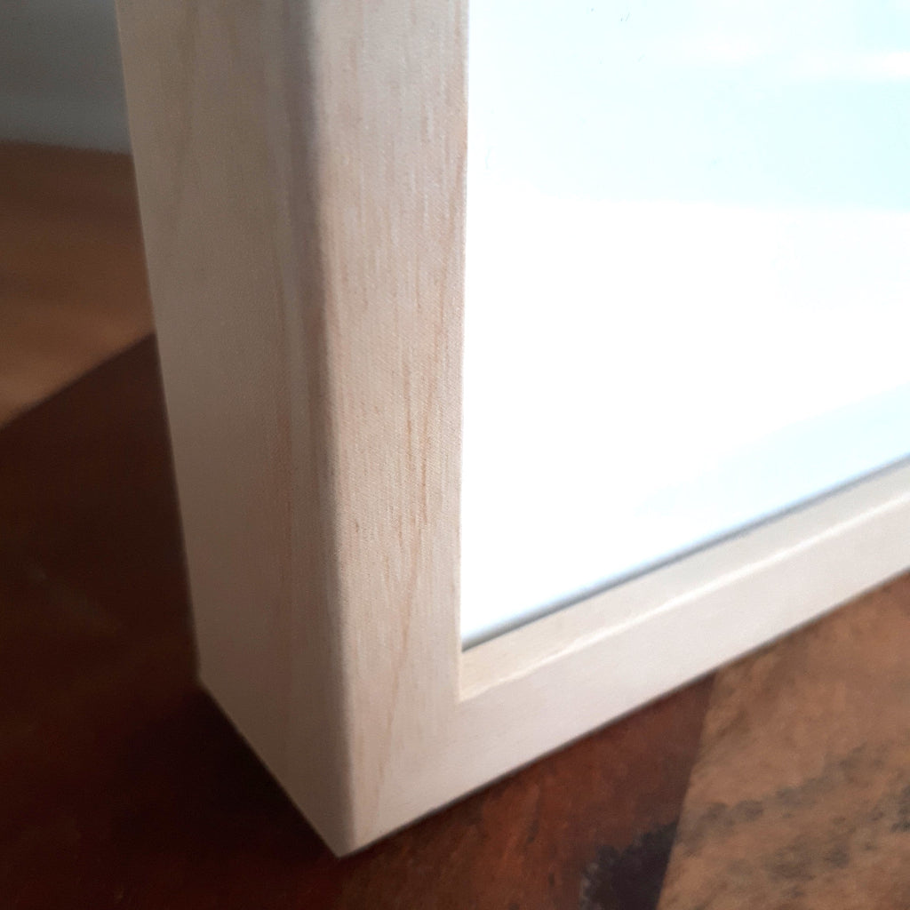 Close-up of a light natural wooden frame corner with white mat