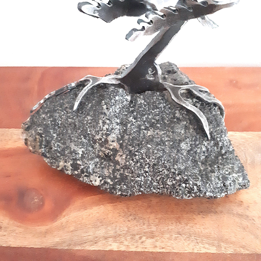 detail of piece of rock and roots of metal tree sculpture
